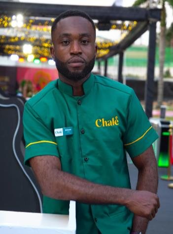 Chalé App crew member in a green uniform shirt, arms folded