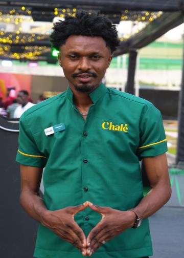 Chalé App crew member in a green uniform shirt with hands together